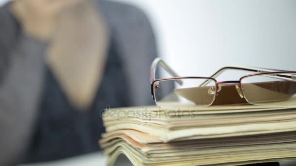 Glasses on a stack of exercise books and female teacher with blurred focus background — Stock Video