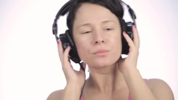 Belle femme dansant dans un casque tout en écoutant une musique sur un fond clair — Video