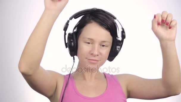 Güzel kadın hafif bir arka plan üzerinde bir müzik dinlerken kulaklık dans — Stok video