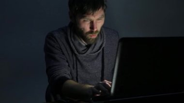 bir dizüstü bilgisayar önünde sakallı adam yeme sandviç