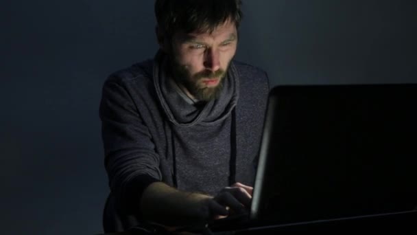 Homem barbudo comendo sanduíche na frente de um laptop — Vídeo de Stock