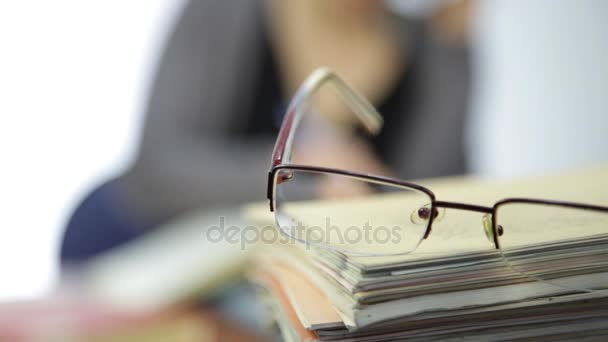 Bril op een stapel boeken van de oefening, vrouw werkt zonder bril na visie correctie — Stockvideo