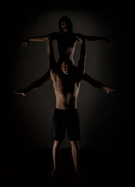 Mladý sportovní pár dělá acroyoga cvičení v temné místnosti — Stock fotografie