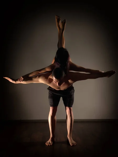 スポーツの男性と女性の暗い部屋で acroyoga の演習を行う — ストック写真