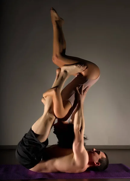 Sportowe, mężczyzna i kobieta robi acroyoga ćwiczenia w ciemnym pokoju — Zdjęcie stockowe