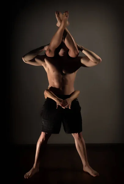 Sport uomo e donna che fanno esercizi di acroyoga in una stanza buia — Foto Stock