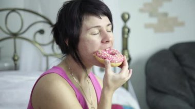 kadın bir yatak, bir çörek yeme abur cubur ile Kahvaltı