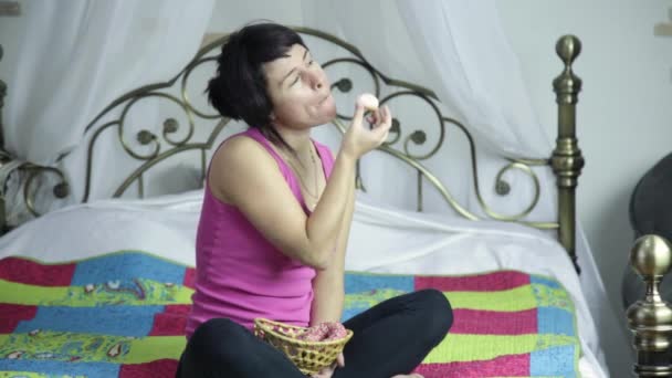 Atleta menina comer donut em uma cama com prazer, proibido e junk food — Vídeo de Stock