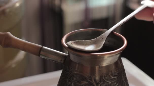 Prepares traditional turkish coffee in copper pot over stove — Stock Video