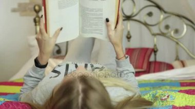 genç kadın evde öğrenme. Kız bir yatak üzerine bir kitap okuma