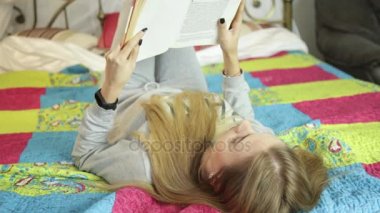 Bir yatakta evde kitap okurken güzel ve genç birbayan. evde öğrenme.