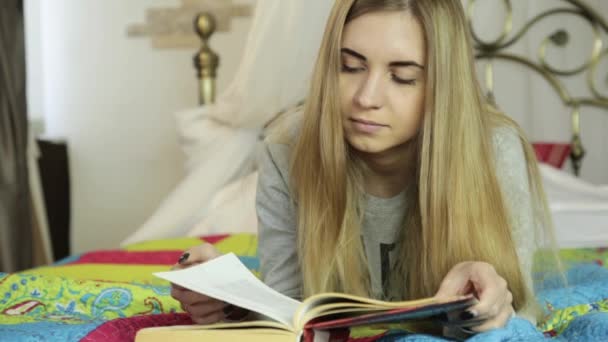 Mujer joven aprendiendo en casa. chica leyendo un libro en una cama — Vídeos de Stock