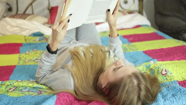 Hermosa joven leyendo un libro en una cama en casa. aprendizaje en casa . — Vídeos de Stock