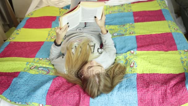 Mooie jonge vrouw lezen van een boek op een bed thuis. thuis leren. — Stockvideo