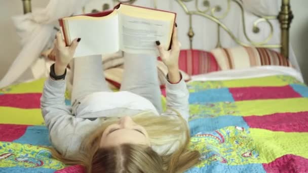 Mulher bonita lendo um livro em uma cama em casa — Vídeo de Stock