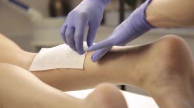 güzellik uzmanı kadın istemciye balmumu Depilasyon pamuk şeritler ile yapıyor