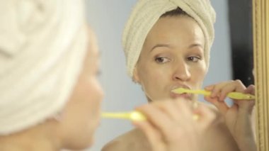 güzel bir kadınla banyoda dişlerini fırçalama bir kafa havluya bir aynada yansıması