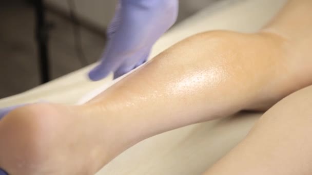 Cosmetologist fazendo depilação de cera com tiras de algodão para cliente feminino — Vídeo de Stock