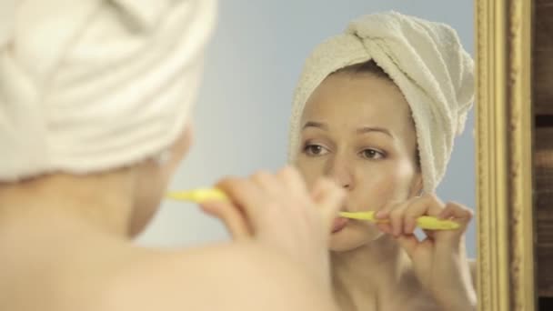 Giovane bella donna con asciugamano su una testa lavarsi i denti in bagno — Video Stock