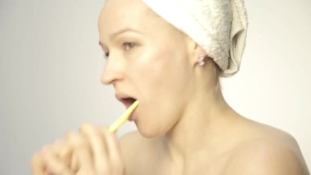 Молодая красивая женщина с полотенцем на голове чистит зубы и танцует — стоковое видео