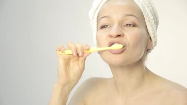 Young beautiful woman with towel on a head brushing her teeth and dancing — Stock Video