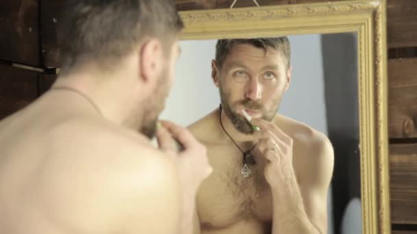 Homme barbu se brossant les dents devant le miroir dans la salle de bain — Video