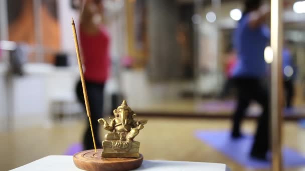 Размытые женщины, занимающиеся йогой, крупным планом статуэтки ганеши и ароматной палочки — стоковое видео