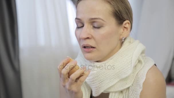 Sad woman heals a runny nose with an onion, sneezes loudly and wipes his nose — Stock Video