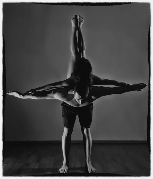 Uomo e donna che fanno esercizi di acroyoga in una stanza buia. bianco e nero — Foto Stock