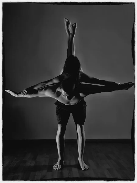 Sportovní, muž a žena, která dělá acroyoga cvičení v temné místnosti. černá a bílá — Stock fotografie