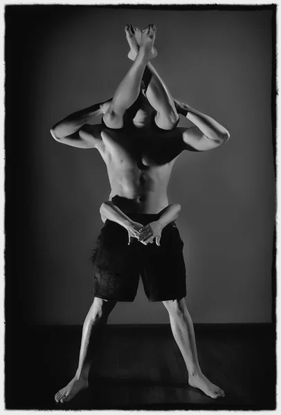 Αθλητικό άνδρα και της γυναίκας που κάνει ασκήσεις acroyoga σε ένα σκοτεινό δωμάτιο. μαύρο και άσπρο — Φωτογραφία Αρχείου