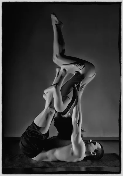 Homem de esportes e mulher fazendo exercícios de acroioga em uma sala escura. preto e branco — Fotografia de Stock