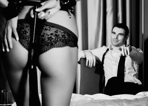 Dominerande sexig kvinnas röv i underwears med en piska stående framför stilig kille. BDSM-konceptet — Stockfoto