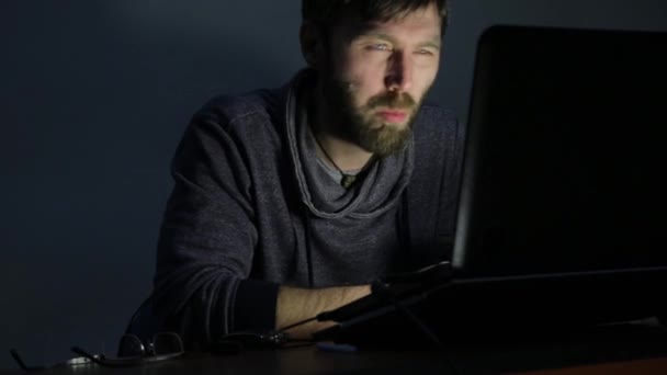 Bebaarde man eten sandwich voor een laptop, werken en begint te verstoren — Stockvideo