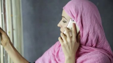 bir cam kenarında duran ve cep telefonuyla konuşmak güzel genç Arap kadın