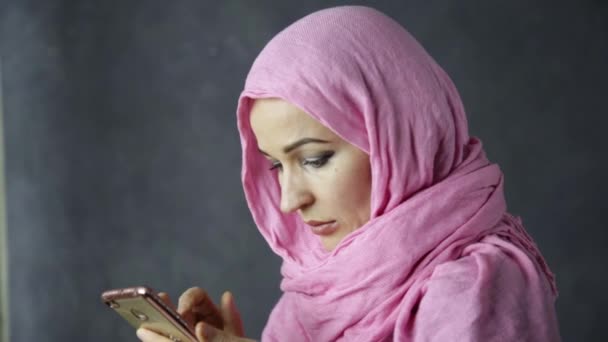 Hermosa joven árabe musulmana mujer en hijab rosa hablando por teléfono celular — Vídeos de Stock