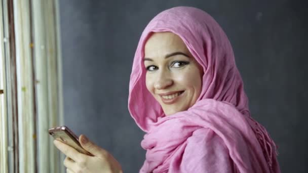 Vacker muslimsk kvinna som pratar i telefonen framför fönstret — Stockvideo