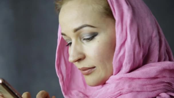 Schöne muslimische Frau im rosafarbenen Hijab, die auf dem Handy spricht — Stockvideo