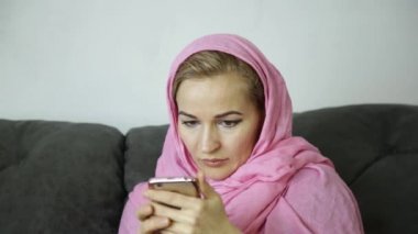 pembe hijab bir kafe ve bir metin cep telefonundan mesaj gönderir bir kanepede oturan güzel Arap kadını