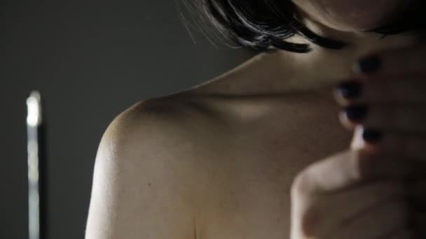 Красива жінка кладе крем на своє плече на темному тлі — стокове відео