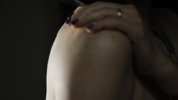 Belle femme met crème sur son épaule sur un fond sombre — Video