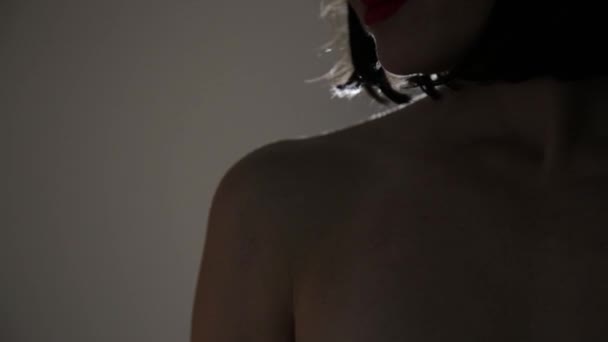 Belle femme met crème sur son épaule sur un fond sombre — Video