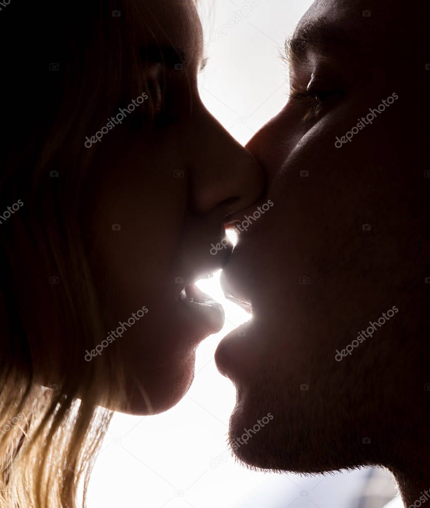 Close-up of young couple in passionately kissing on bright background