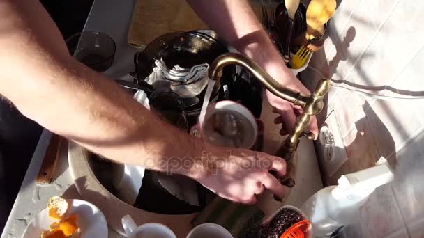 Close-up mans handen wast een gerechten, waterstraal rinses de platen van schuim en afwasmiddel — Stockvideo
