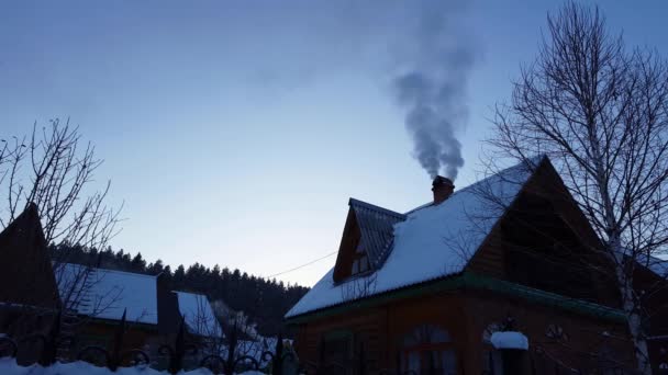 Houten huis in de bergen. rook uit de schoorsteen actie in de winter. — Stockvideo