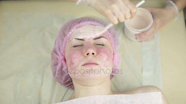 Kvinnan får en kosmetisk medicin behandling, rengöring ansikte hud med mask — Stockvideo