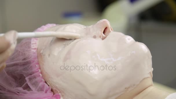 Esteticista aplicación de mascarilla facial en una cara de mujer, limpieza de tratamiento de la piel — Vídeo de stock