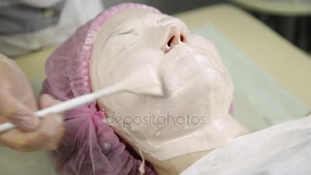 Beautician mengenakan masker wajah pada seorang wanita, membersihkan perawatan kulit — Stok Video