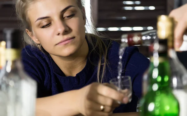 Uma mulher triste e solitária bebe álcool no bar, muitas garrafas vazias à sua volta. conceito de questão social, alcoolismo feminino — Fotografia de Stock