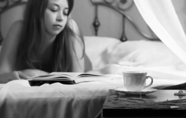 Mladá krásná sexy žena čtení knihy na posteli v hotelovém pokoji. černá a bílá — Stock fotografie